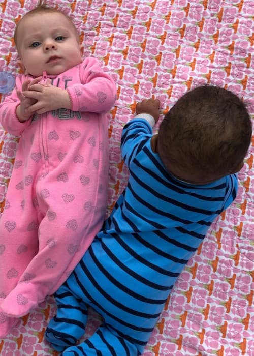 two babies lying down together playing