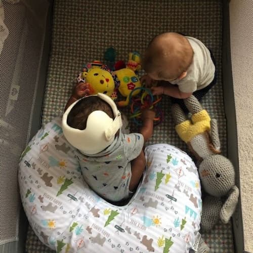 two kids playing together in a play pen
